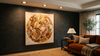 A cozy living room with a dark accent wall featuring a large circular abstract painting in warm tones. A brown sofa sits beside a side table with a lamp.